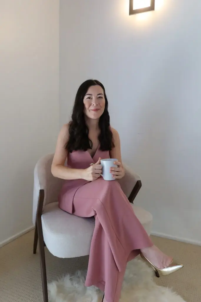 Tracy seated at home, holding a mug