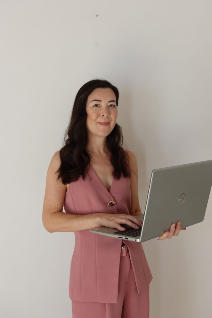 Tracy, founder of The Reclaim Motherhood Method, standing with her laptop